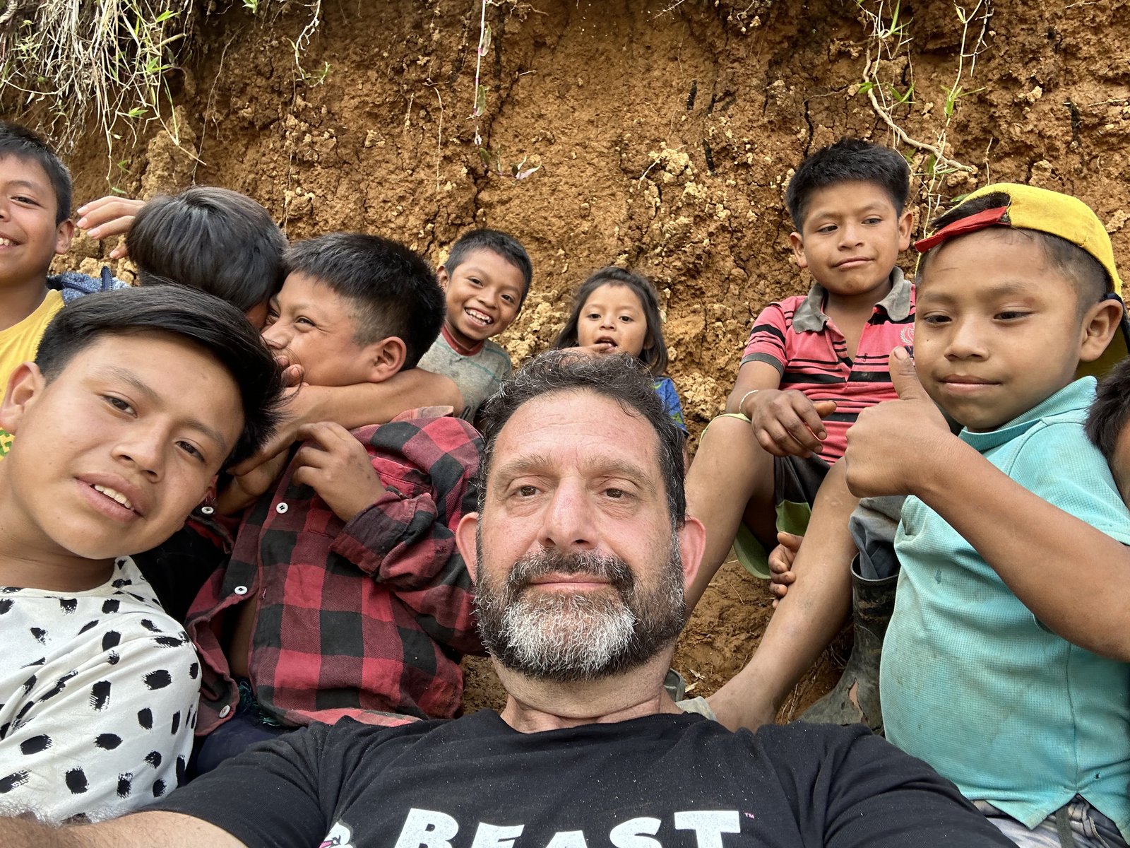 Darren Margolias surrounded by Guatemalan children climbing on him in a hillside village