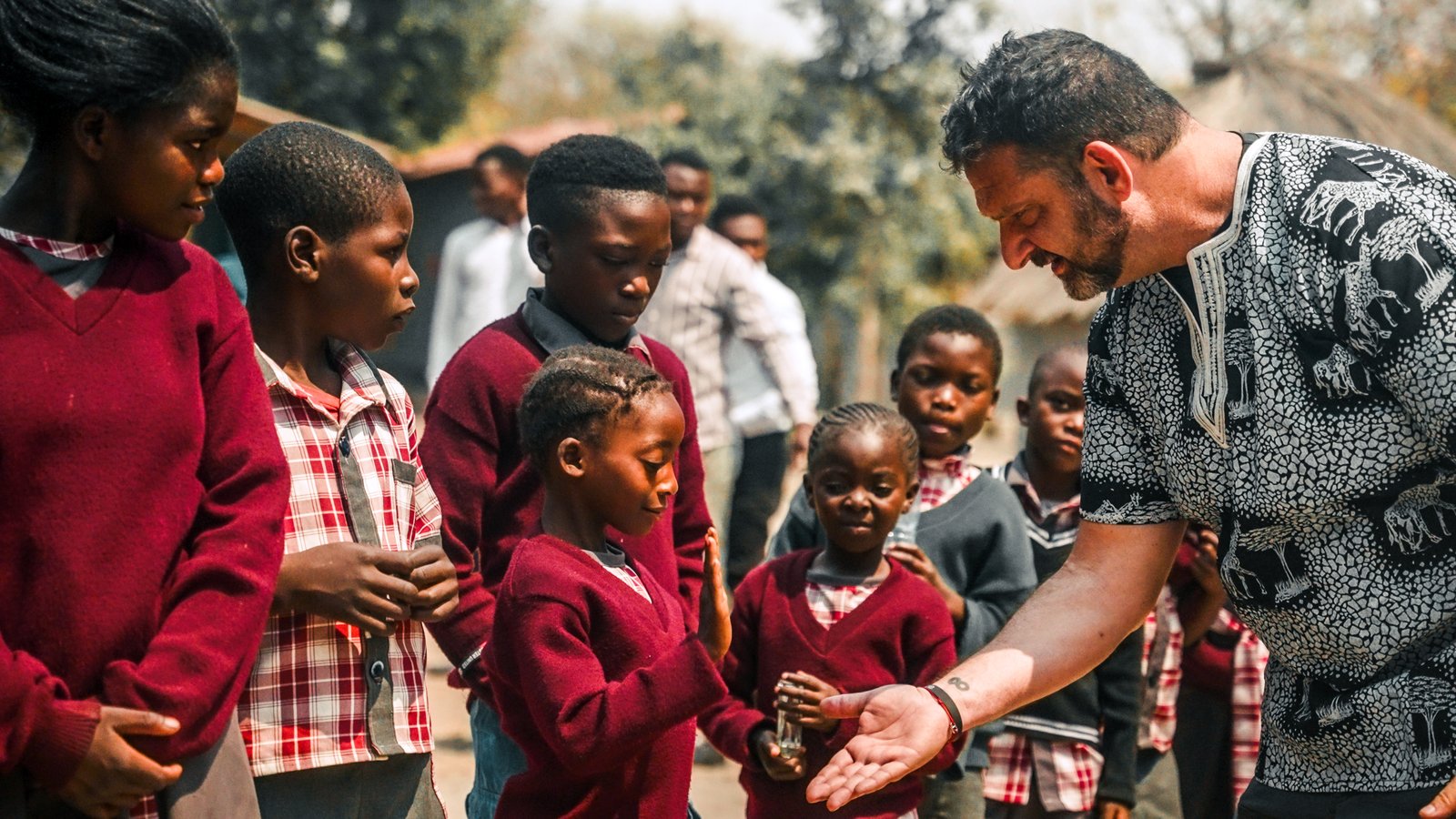 Darren Margolias sharing a moment with Zambian schoolchildren in red uniforms